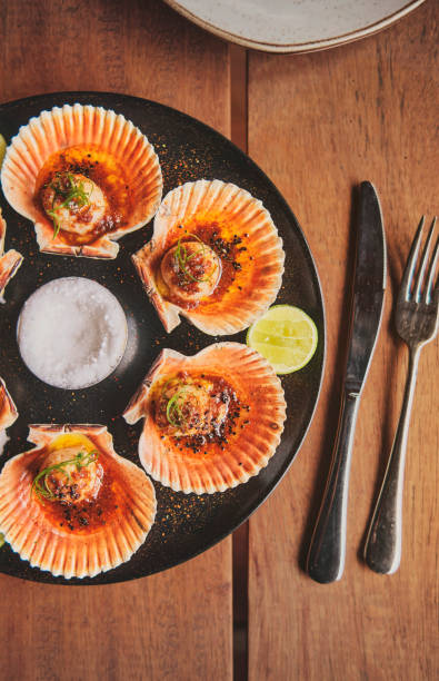 istock Scallops with flamed shells on a black plate. Luxury restaurant food. Seafood, selective focus. 1391487723