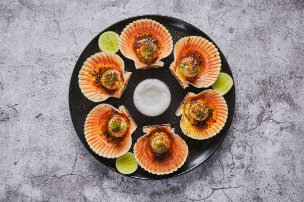 istock Scallops with flamed shells on a black plate. Luxury restaurant food. Seafood, selective focus. 1391487728