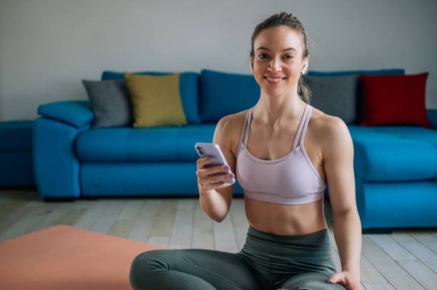 istock Woman using airpods and a smartphone while training at home 1391495105
