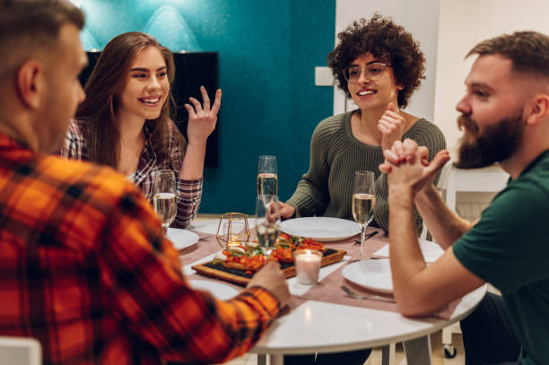 istock Group of friends enjoying dinner while sitting at the kitchen table together 1391495182