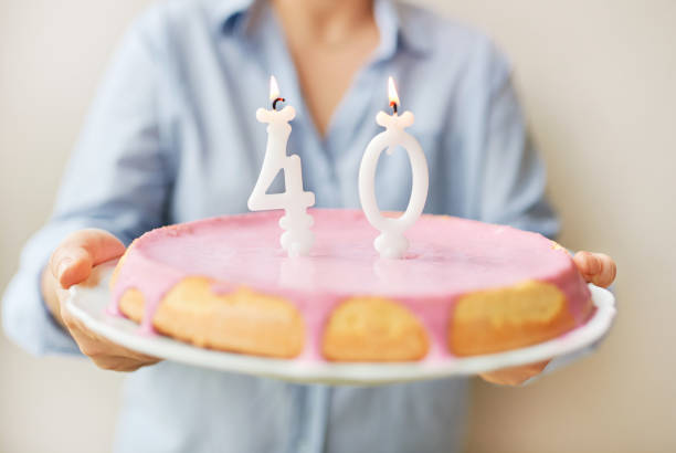 Happy middle age 40 year old woman holding cake with candles stock photo