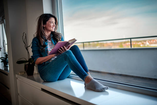 istock Woman reading a book, resting and looking through window 1391503699