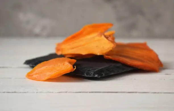 Photo of a pile of persimmon chips on a stone black plate