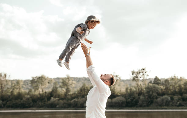 Father tossing happy kid in air stock photo