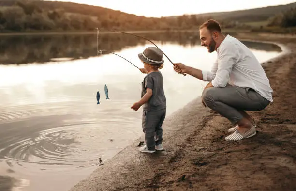 Photo of Father and son fishing together near lake