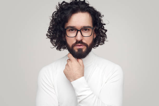 istock Trendy young bearded man looking at camera in white studio 1391504868