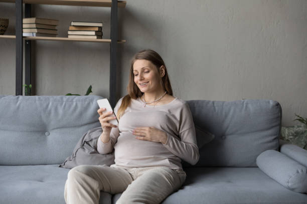 istock Smiling young pregnant woman using cellphone at home. 1391505462