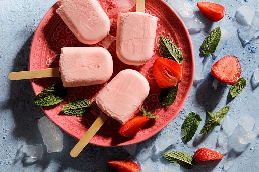 Homemade strawberry ice cream popsicles on a plate.