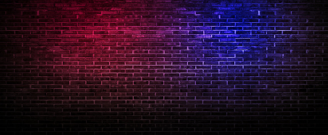 Black brick wall background rough concrete with neon lights and glowing lights. Lighting effect pink and blue on empty brick wall background