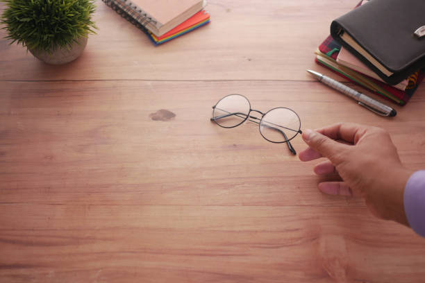 rear view of man hand holding old eyeglass on table .