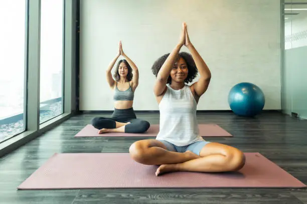 Asian  and African American woman friend doing Yoga Pilates workout together.Close up of the hands of a woman doing yoga in the gym With a group.