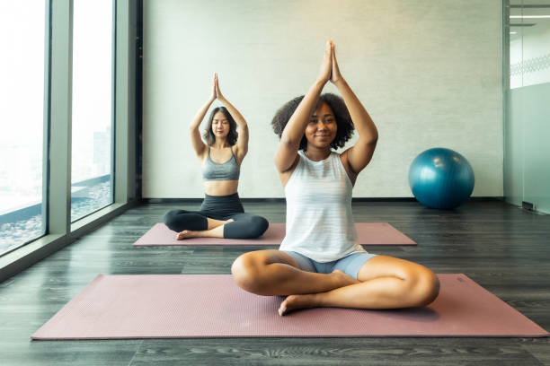 amiga asiática e afro-americana fazendo yoga pilates treino juntos. feche acima das mãos de uma mulher fazendo ioga na academia com um grupo. - aula de ioga - fotografias e filmes do acervo