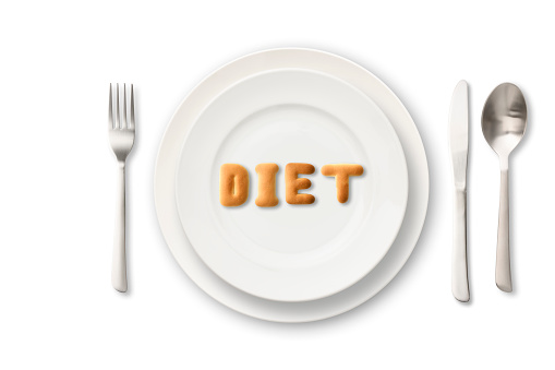 DIET letters written by cookies on white plate with silverware.\nDiet concepts.