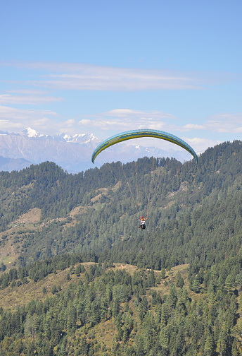 Mandi, Himachal Pradesh, India - 10 16 2021: A young guy enjoying paragliding with professional pilot in the sky with mountain and glacier view