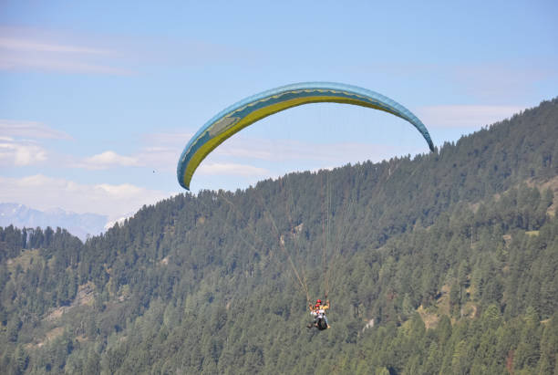 Photo of a young male tourist enjoying paragliding with professional pilot in the sky Mandi, Himachal Pradesh, India - 10 16 2021: Photo of a young male tourist enjoying paragliding with professional pilot in the sky para ascending stock pictures, royalty-free photos & images