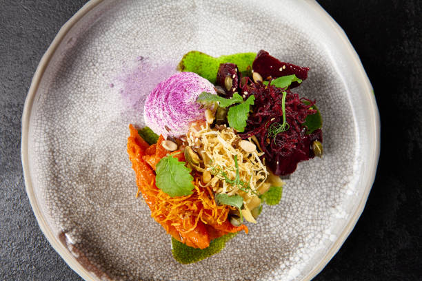 istock Baked root vegetables in handmade ceramic dishware. Vegan food - caramelized carrot, beetroot and celery on modern crockery. Vegetarian food innovative recipes 1391547820