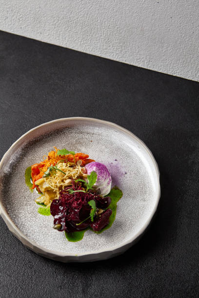 istock Baked root vegetables in handmade ceramic dishware. Vegan food - caramelized carrot, beetroot and celery on modern crockery. Vegetarian food innovative recipes 1391547821