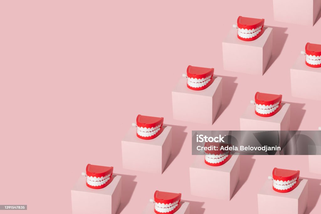 Creative pattern with teeth toy on pastel pink cube on pastel pink background. 80s or 90s retro fashion aesthetic concept. Minimal romantic smile idea. Dental Health Stock Photo