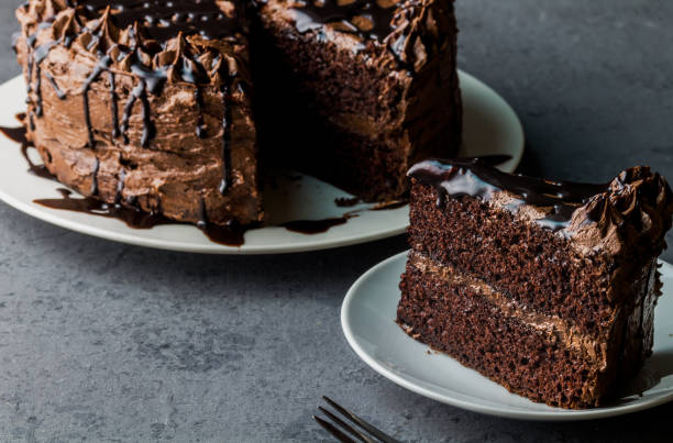 istock Slice of chocolate cake with whole cake defocused in background 1391548495