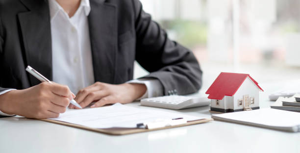 istock Pen handles signed documents with model houses and laptop on the table. 1391549634