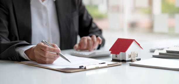 istock Businessman or Bank officer working on office table with using calculator to calculate Financial budget, loan document, Price of house. Real estate agent and home loan concept. 1391549646