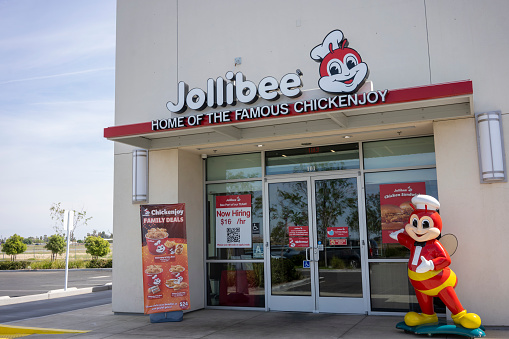 Delano, CA, USA - Mar 26, 2022: The entrance to a Jollibee restaurant in Delano, California. Jollibee is a Filipino multinational chain of fast food restaurants owned by Jollibee Foods Corporation.