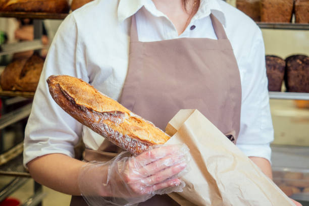 istock Cheerful baker delivering bread to client in store 1391550910