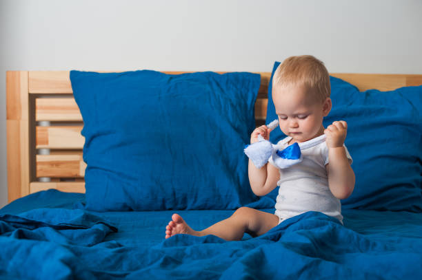 istock Toddler boy plays with Easter bunny ears on bed close-up. 1391553034