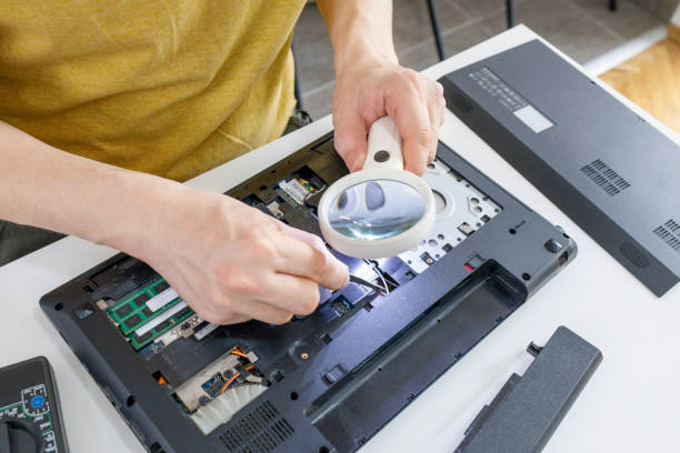 istock Man using glass magnifier when repairing a laptop 1391554295