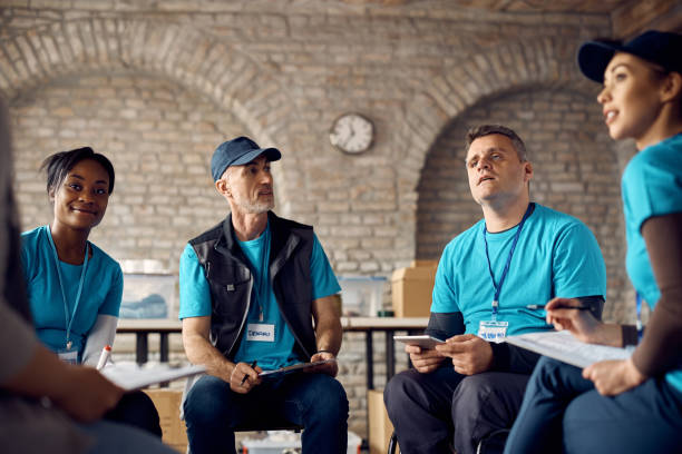 istock Group of volunteers talking while sharing duties on a meeting at donation center. 1391554504