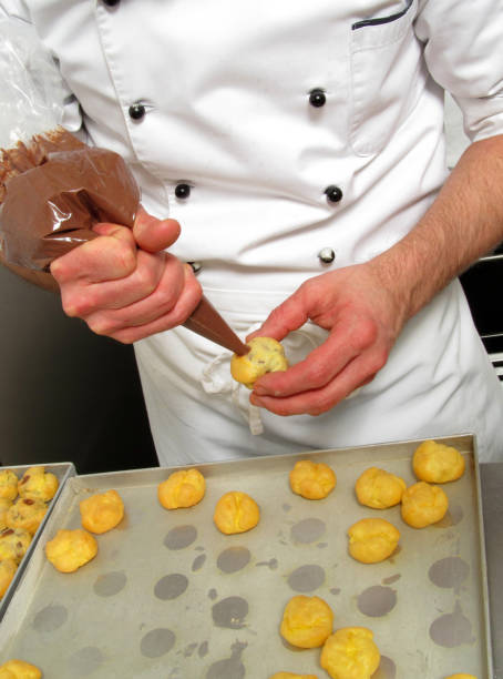 istock pastry cook injecting chocolate cream on sweets. 1391555696