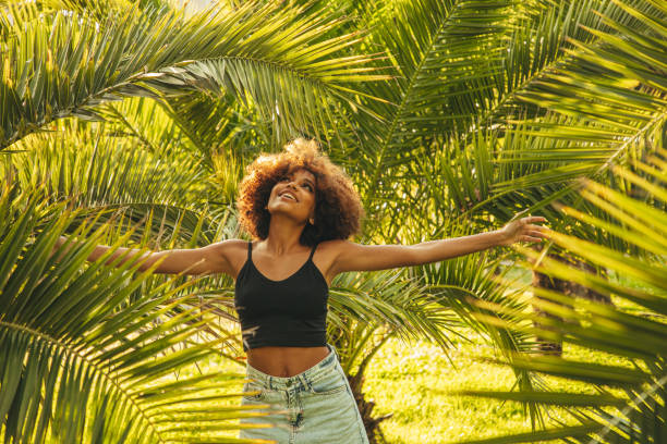 istock Pretty young afro woman among palm trees 1391558504