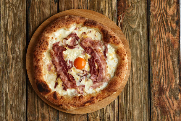 istock Carbonara pizza with bacon and egg on wooden background 1391559892