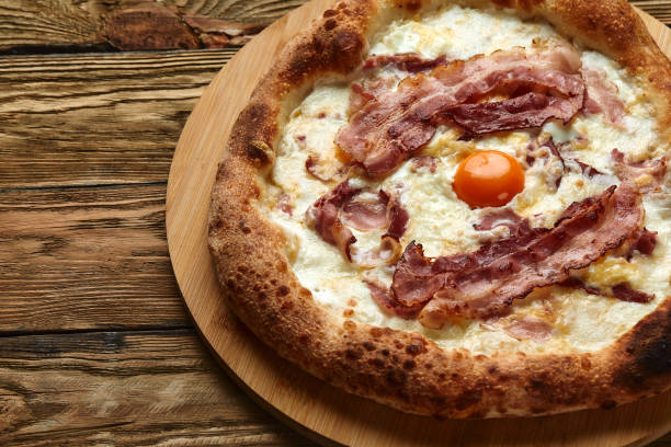 istock Carbonara pizza with bacon and egg on wooden background 1391560465