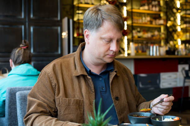 um homem adulto loiro de 40 a 45 anos almoçando em um café em um shopping center - male 45 years old - fotografias e filmes do acervo