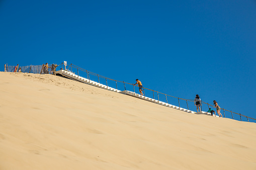 Tourists walking up the stairs on the east side of the Dune of Pilat on a summer day in Gironde, France
