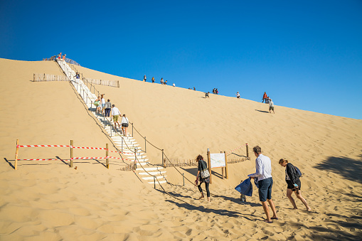 Tourists walking up the stairs on the east side of the Dune of Pilat on a summer day in Gironde, France