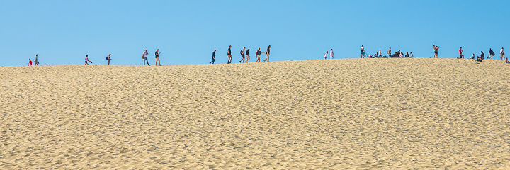 Silhouettes of tourists visiting the top of the Dune du Pilat during summer in Gironde, France