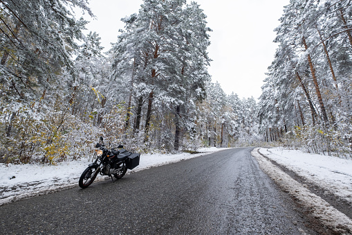Motorcycle on the road in snowy mountain pine forest. Winter motor travel