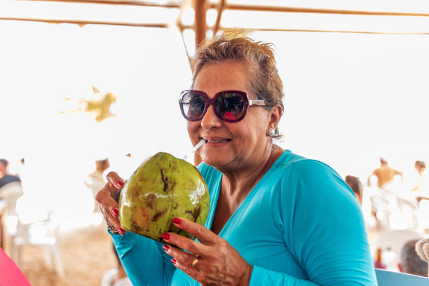 istock Attractive senior Hispanic woman drinking Coconut water 1391564395