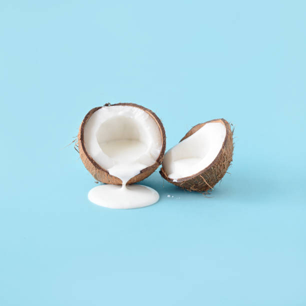 Coconut with milk on a blue background. Coconut with milk on a blue background. Minimal still life fruit concept. Summer aesthetic idea. coconut milk stock pictures, royalty-free photos & images