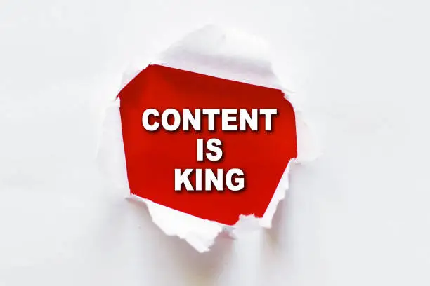 Photo of Content Is King text on red background under white torn paper