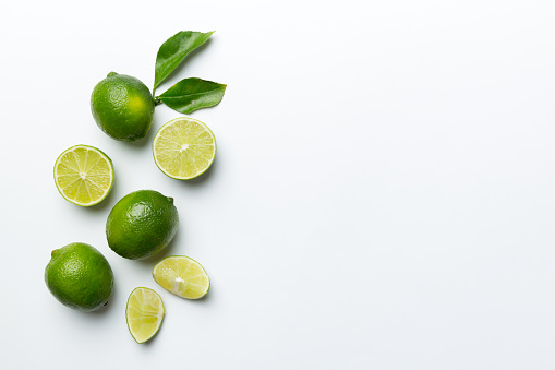 Lime fruits with green leaf and cut in half slice isolated on white background. Top view. Flat lay with copy space.