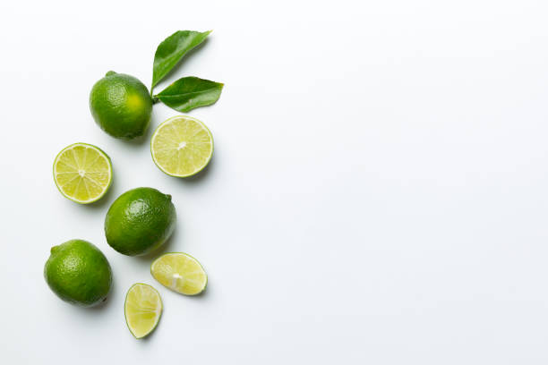 Lime fruits with green leaf and cut in half slice isolated on white background. Top view. Flat lay with copy space stock photo