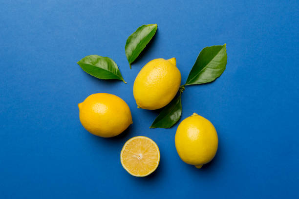 istock Many fresh ripe lemons with green leaves on colored background, top view, space for text 1391566845