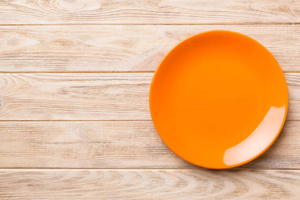 istock Top view of empty orange plate on wooden background. Empty space for your design 1391566865