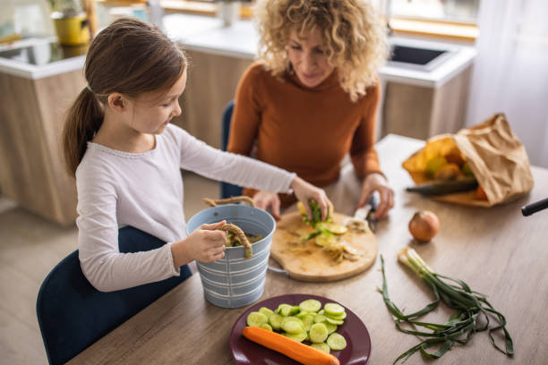 istock Mother and daughter collecting leftovers from vegetable for compost 1391567281