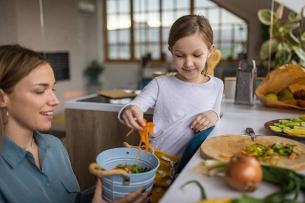 Mother and her daughter in the kitchen using leftovers for compost