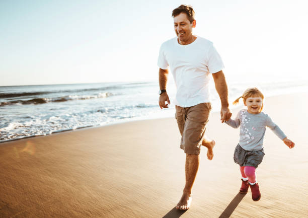 istock dad and daughter walking on the beach 1391567990