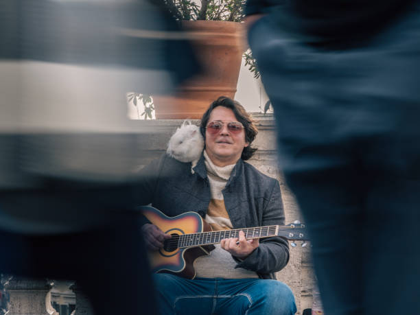 Busker plays the guitar above the Spanish Steps in Rome. His furry friend stays on his shoulder.